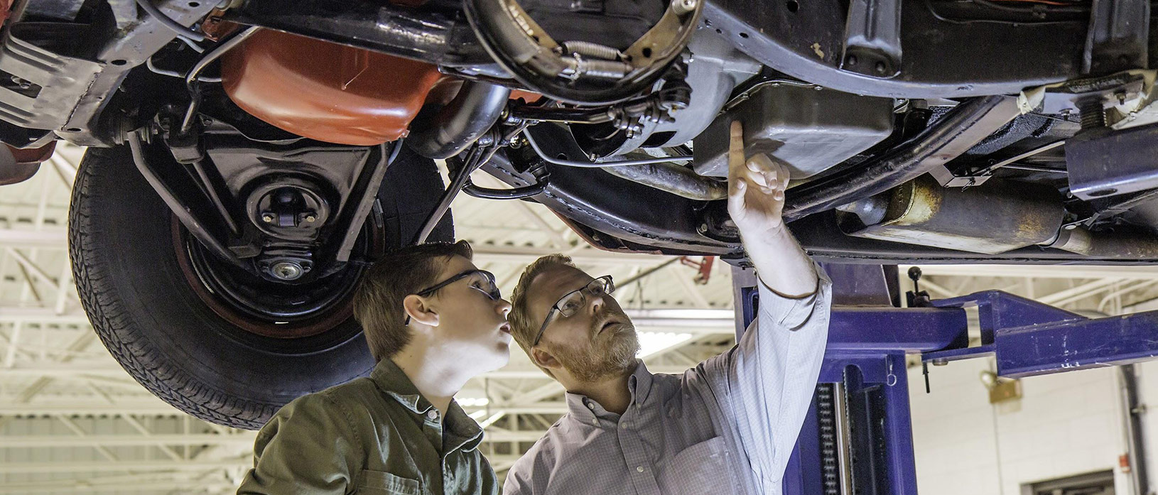 Two men examining the undercarriage of a car.