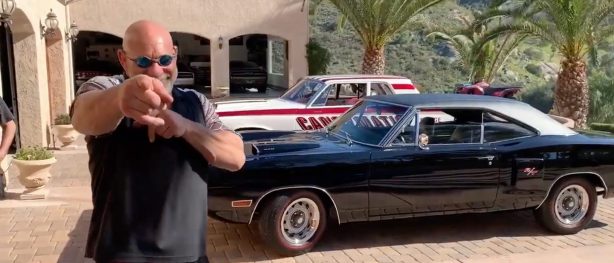 Bill Goldberg standing in front of his car collection outside of his garage at his home