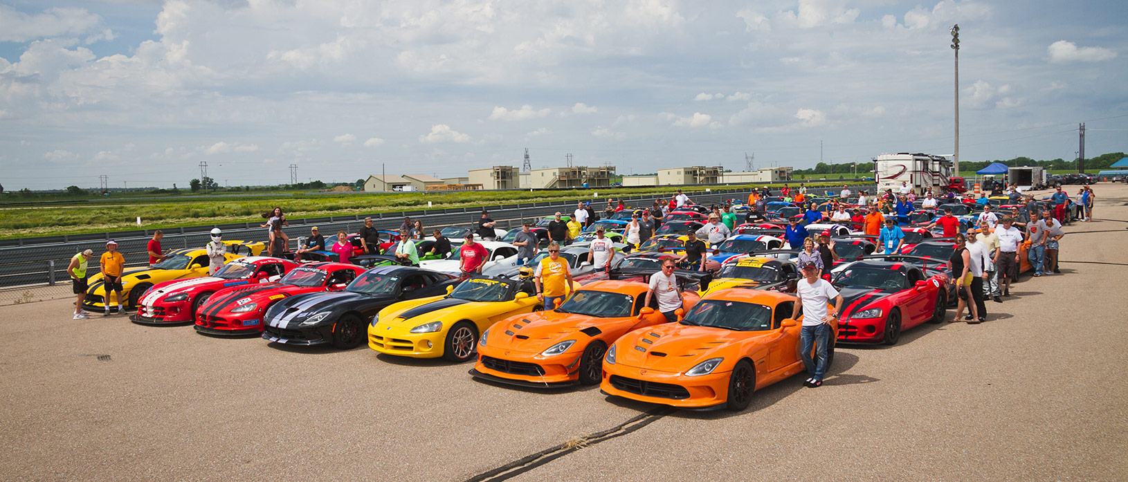 dodge vipers lines up and all their owners standing next to them