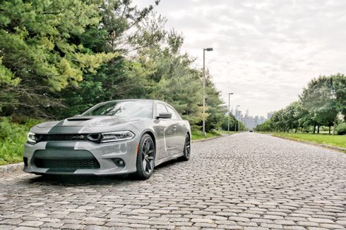 a dodge charger parked on a cobblestone road