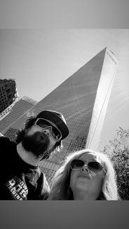 a man and woman with a city building behind them