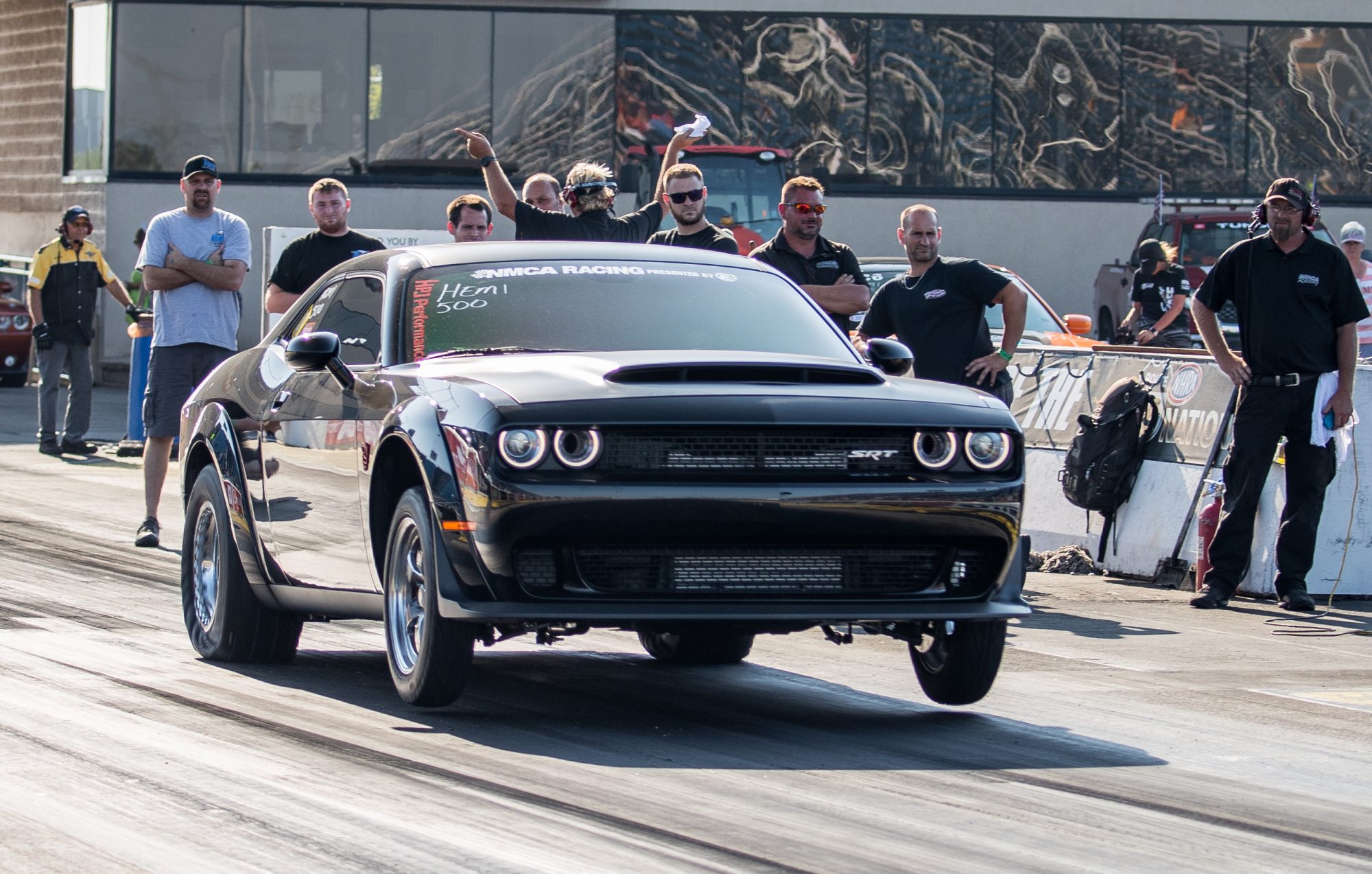 dodge vehicle on two wheels at the starting line of a drag strip 