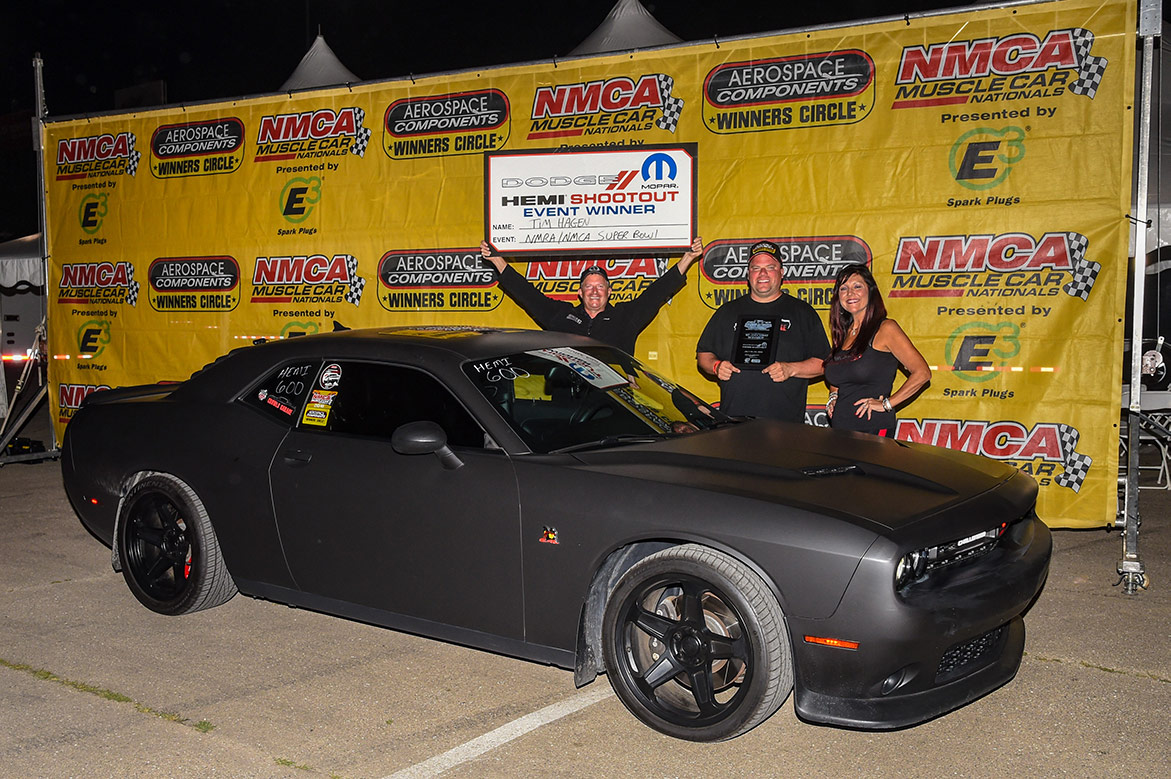 two men and one woman holding a prize next to a dodge vehicle