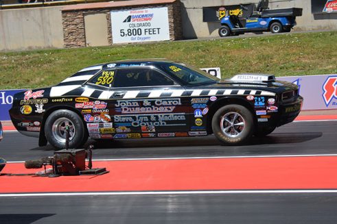 a vehicle covered in decals on the starting line of a drag strip