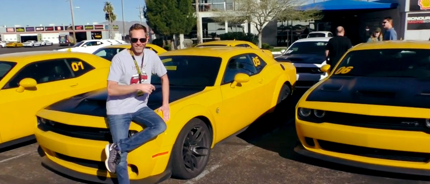 Man sitting on the hood of a yellow Dodge Challenger SRT Hellcat