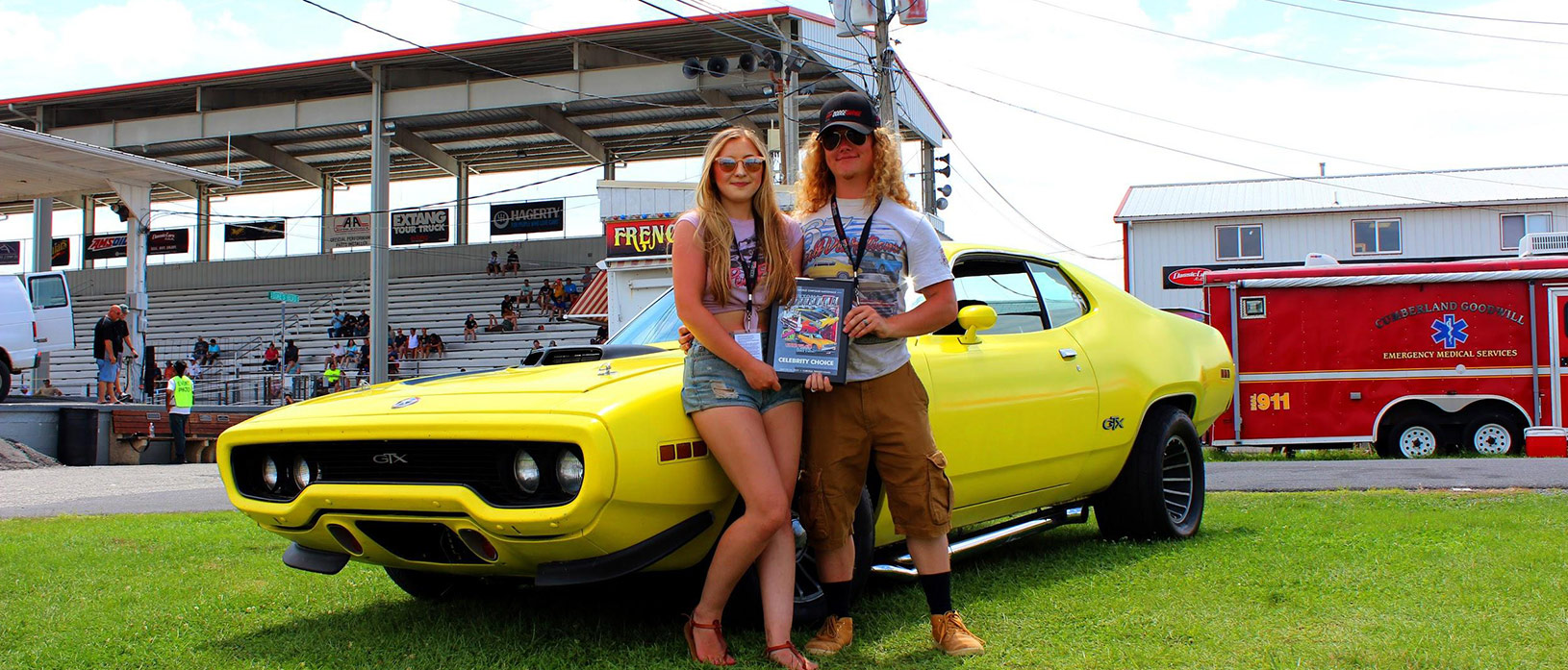 man and woman next to yellow 1971 Plymouth GTX