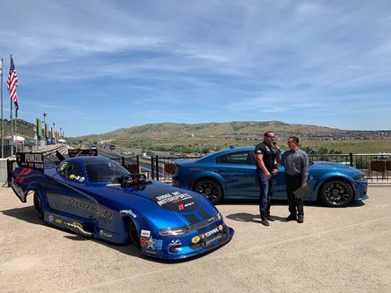 two men standing by a 2020 dodge charger srt hellcat widebody funny car