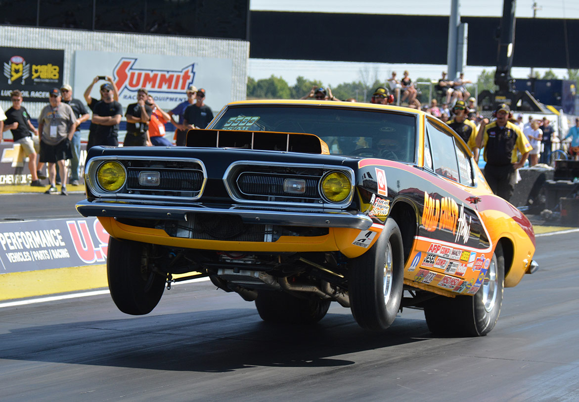 dodge vehicle on two wheels racing down a drag strip