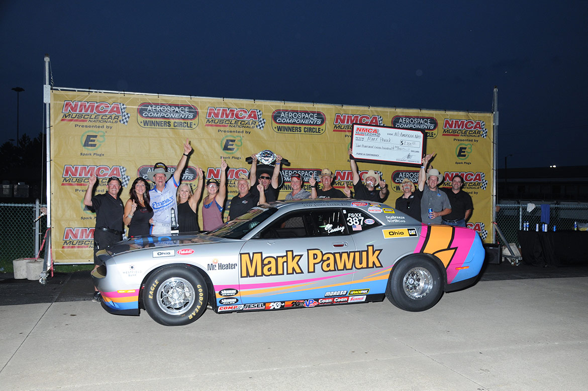 group of people celebrating a win around a vehicle