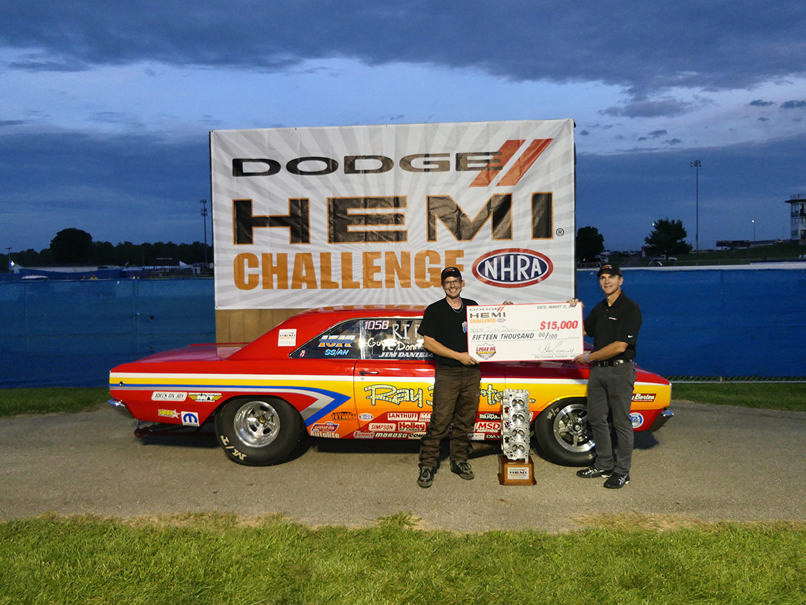 two men standing with a large check in front of a dodge vehicle