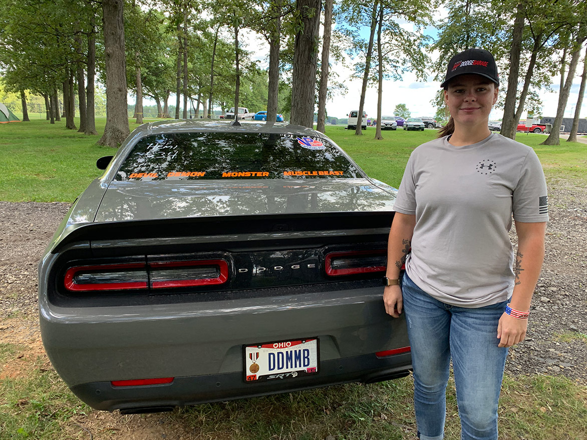 woman standing next to a dodge vehicle