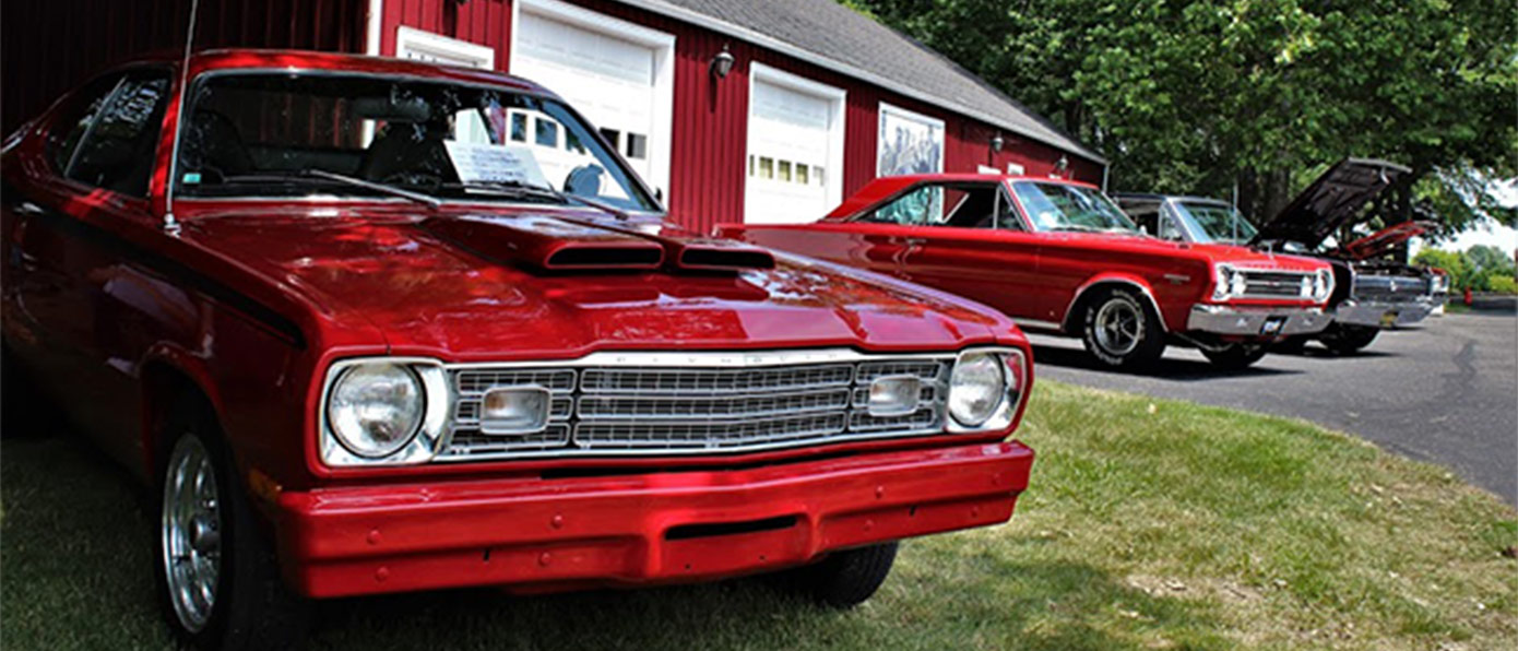 red cars parked outside next to a red barn