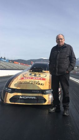 man standing next to a funny car