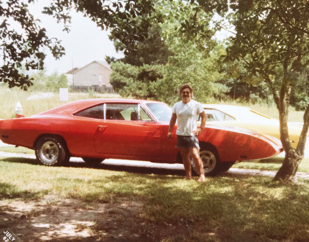 man standing next to a dodge vehicle