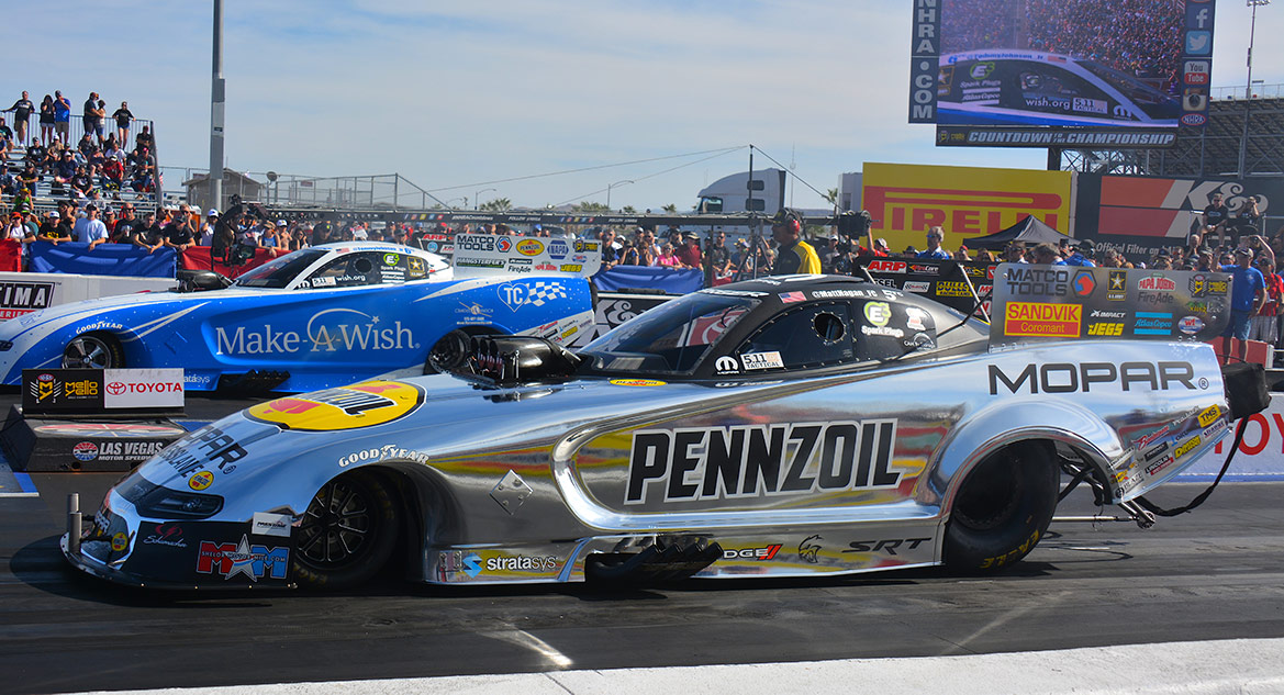 funny cars on the starting line of a drag strip