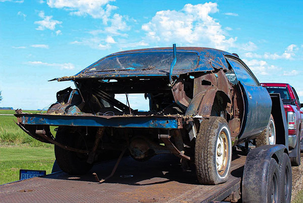 decrepit plymouth vehicle on a trailer bed