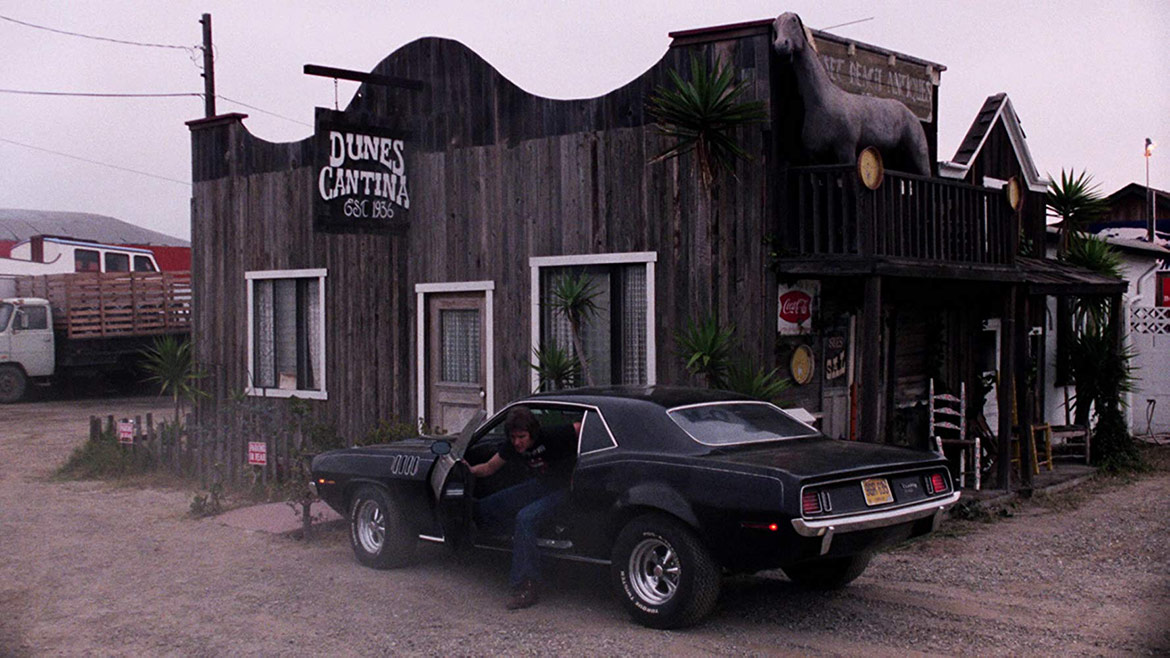 man getting out of a vehicle parked outside a bar