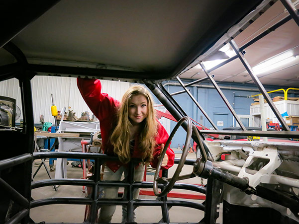 Olivia peering through a vehicle body