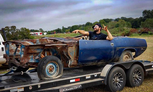 man sitting in decrepit plymouth vehicle