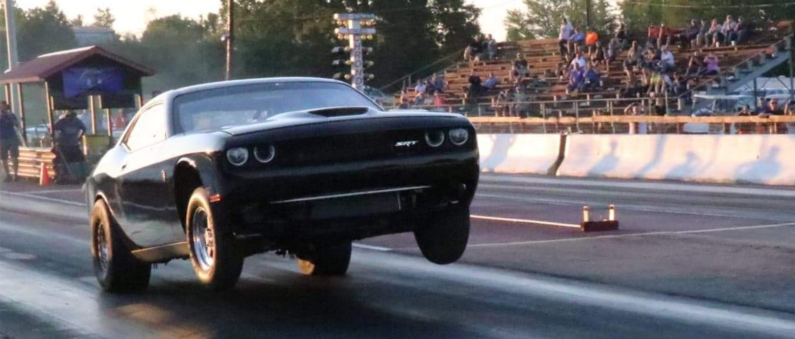 dodge vehicle on two wheels racing down a drag strip