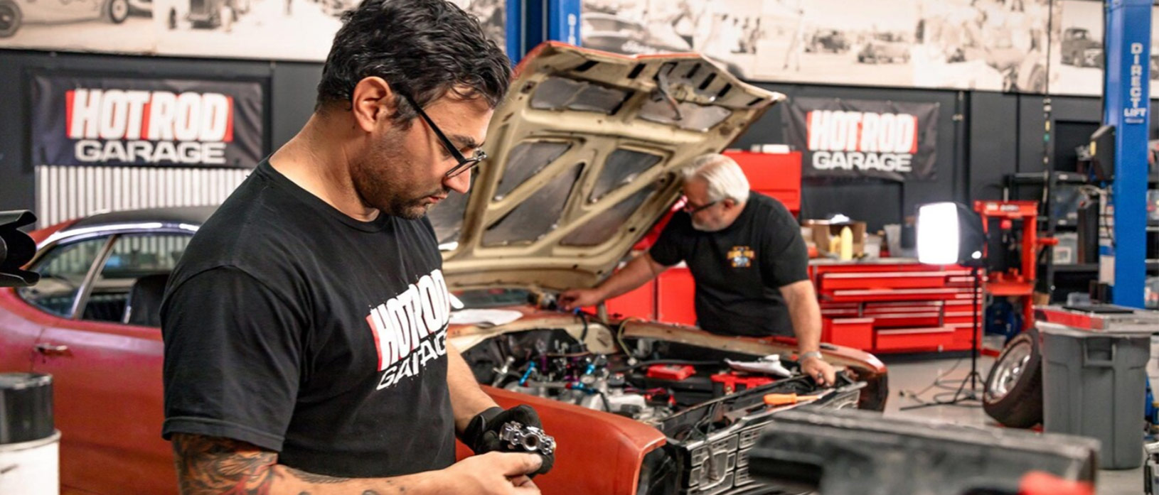 two men working on a car in their garage