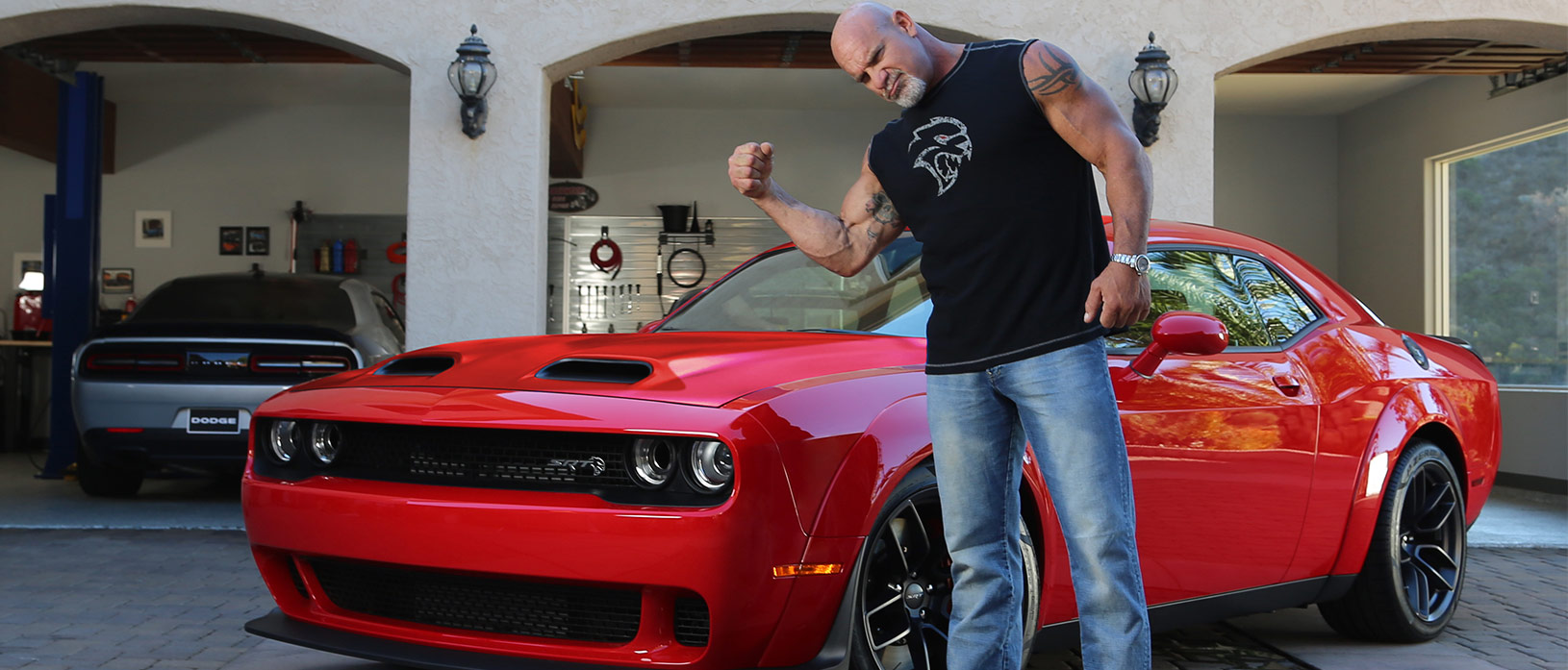 bill goldberg flexing next to his dodge vehicle