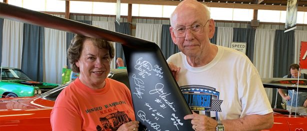 man and woman with autographed vehicle part