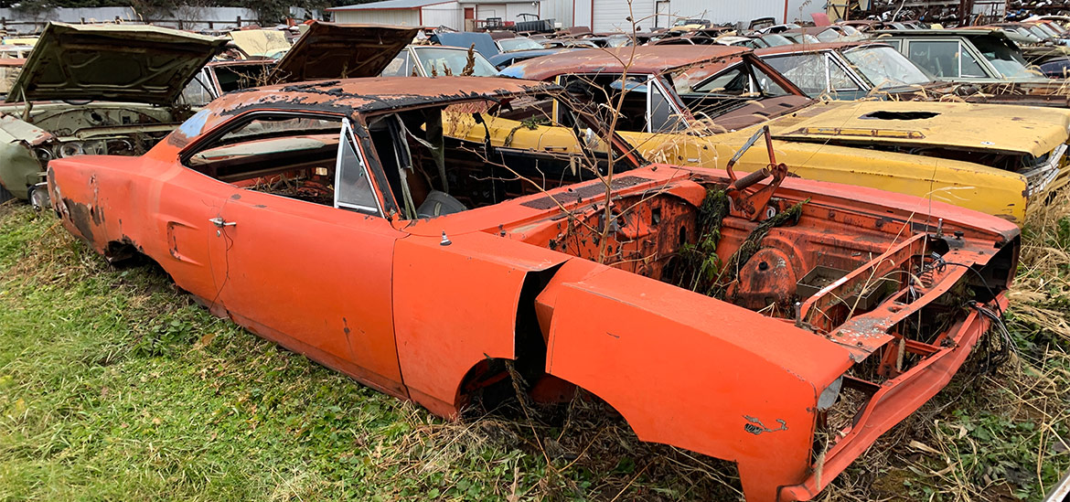 row of mopar vehicles in junkyard