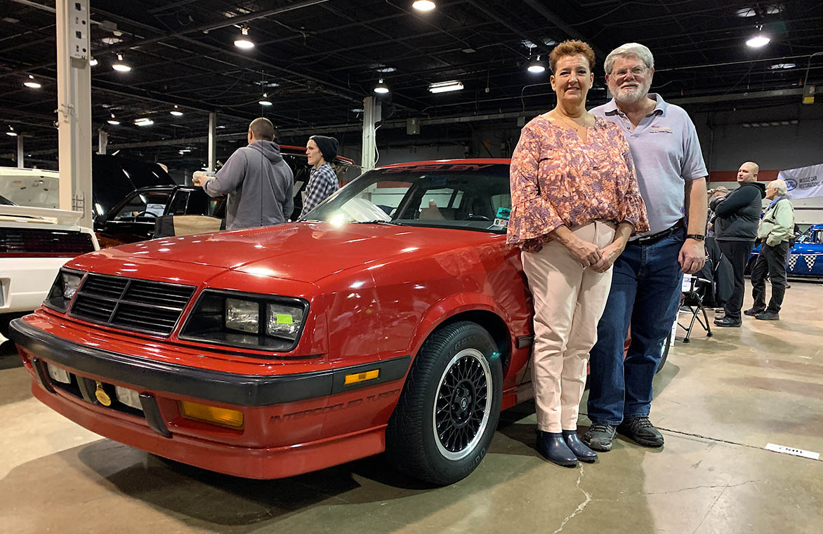 Man and woman standing next to Shelby Lancer