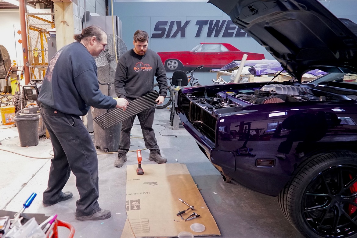 two men putting grill on car