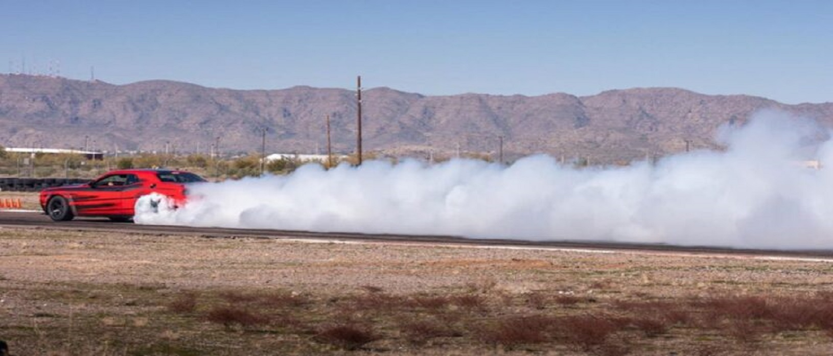 Dodge Hellcat Redeye driving on Bondurant track with smoke coming off back tires