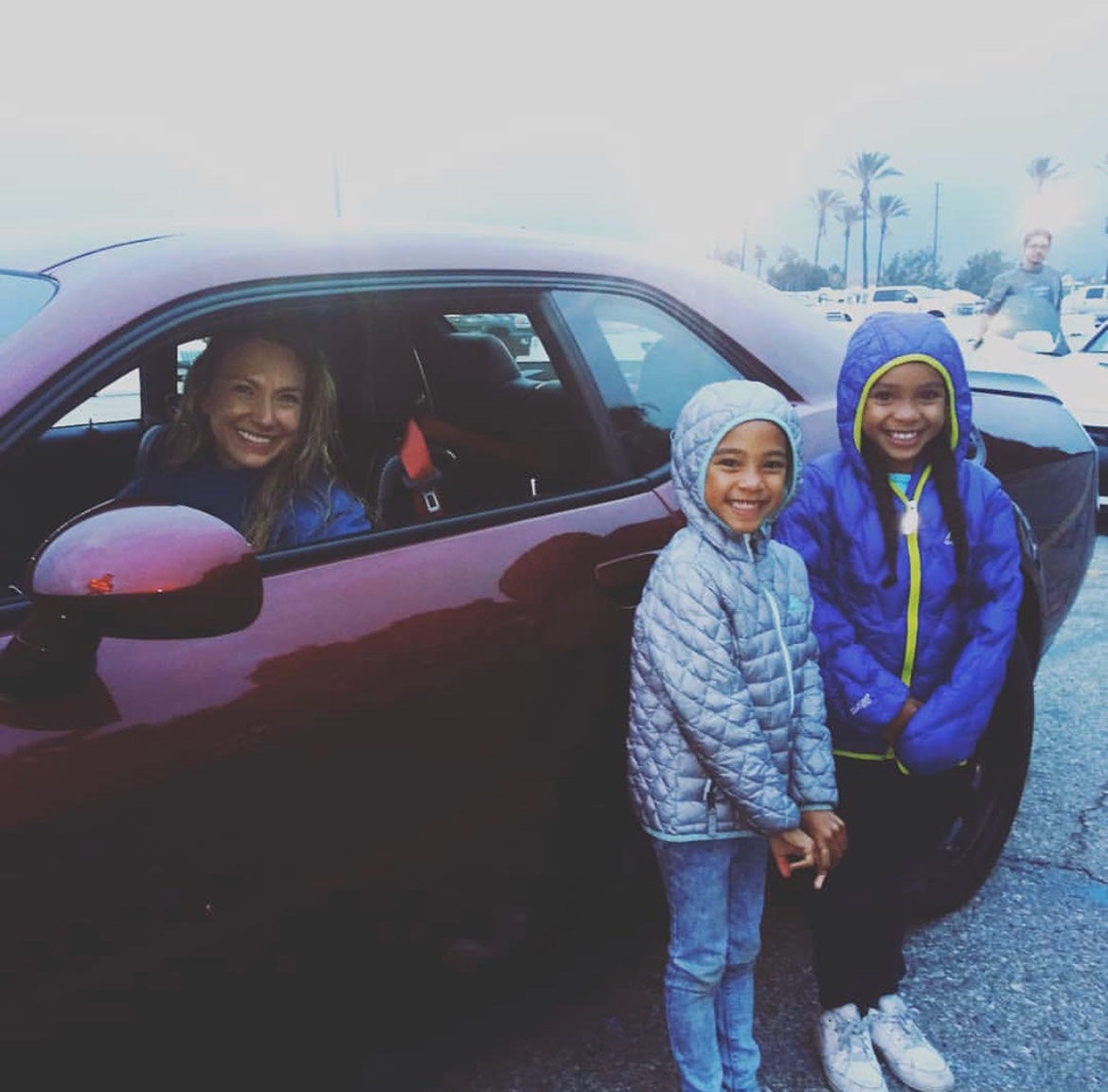 woman in a car and two little girls standing outside the car