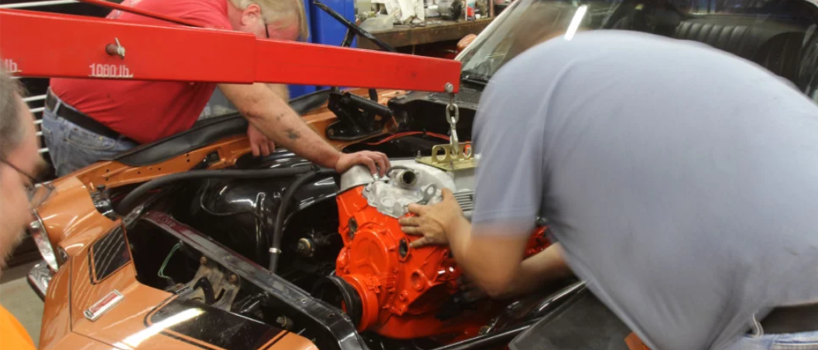 three men working on a car engine