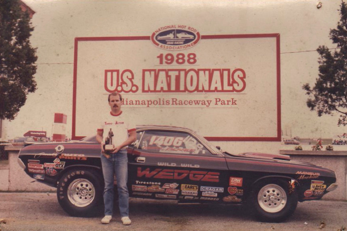 old picture of a man with a trophy and his vehicle