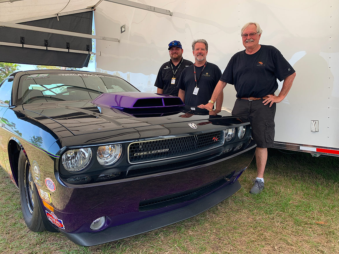 three men with a dodge challenger