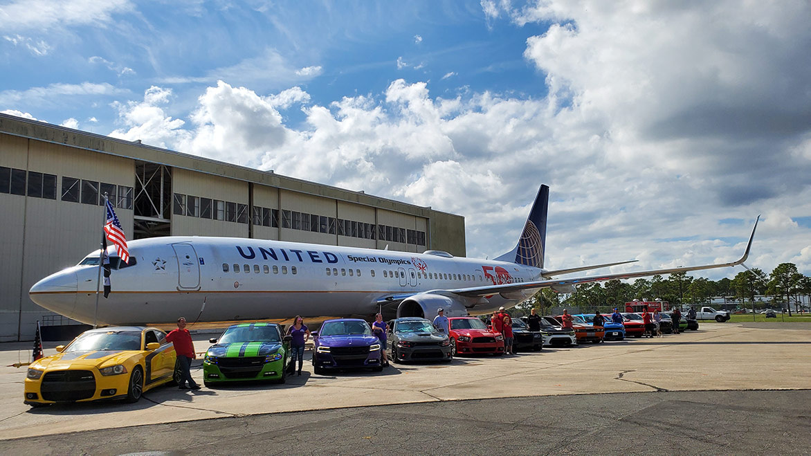 cars on display in front of a jet airplane