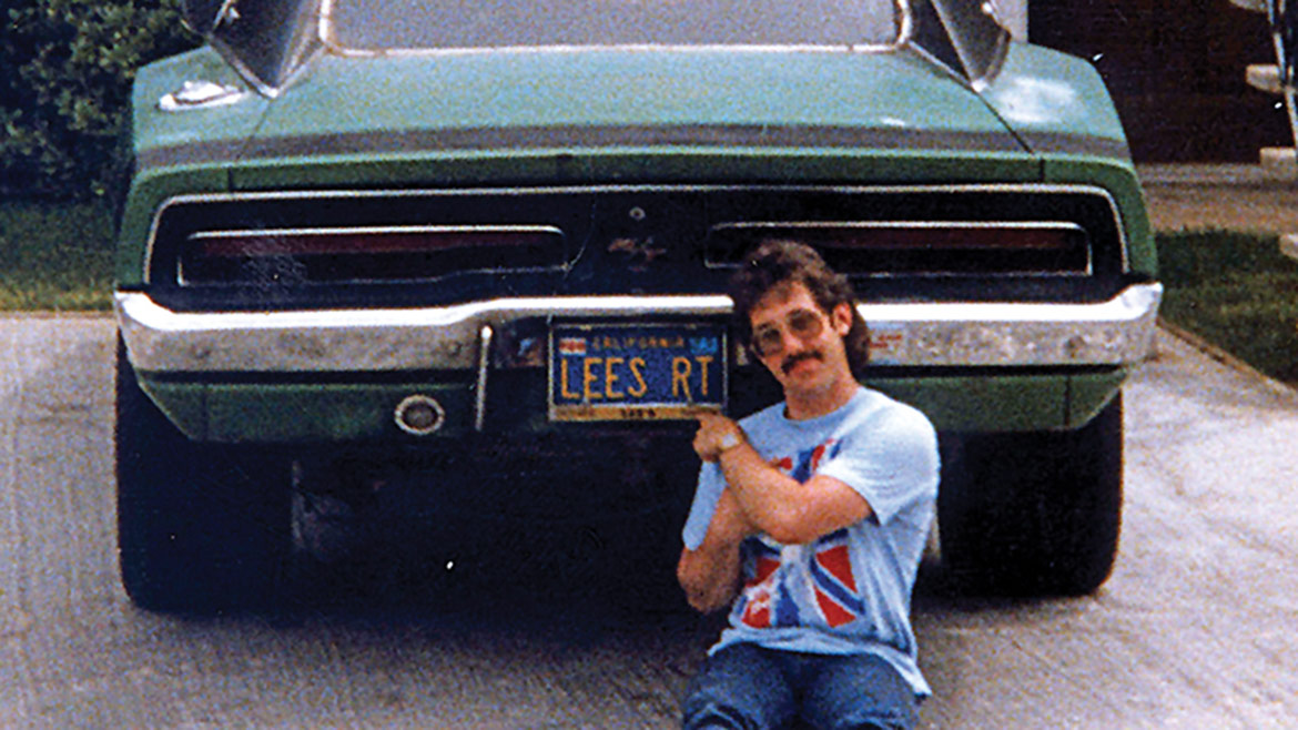 lee storz pointing at his vehicle license plate that says "Lee's RT"