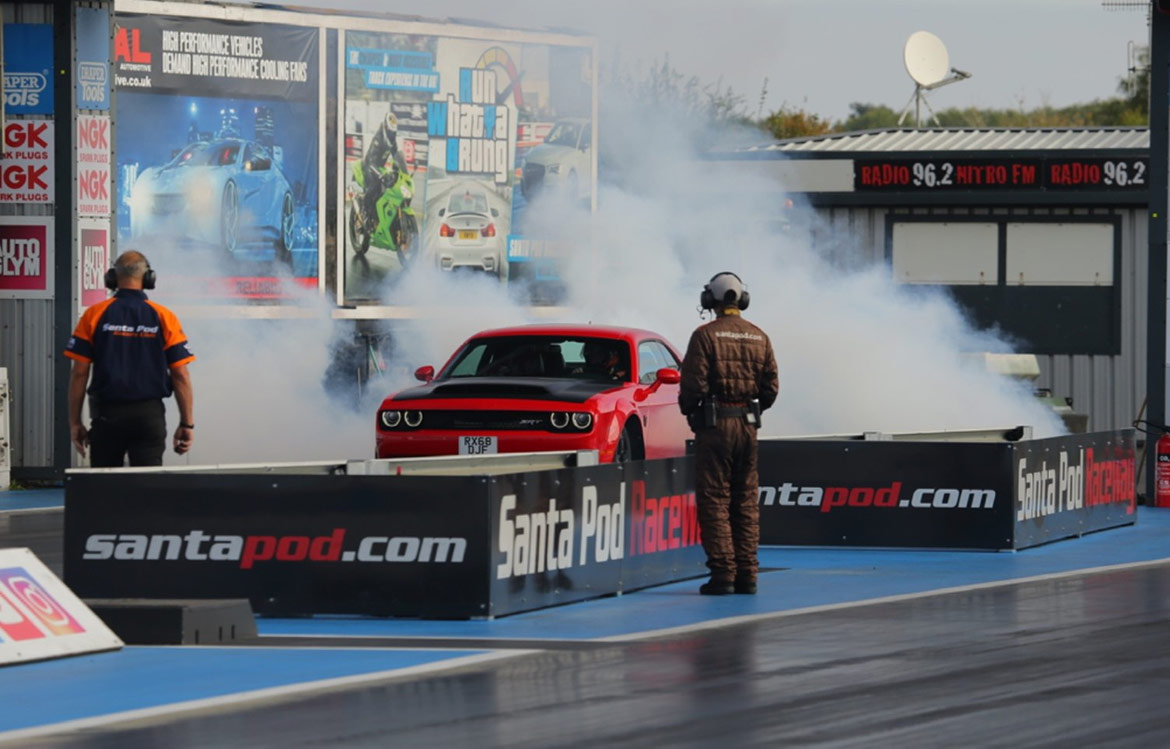 Dodge vehicle doing a burnout on the starting line of a drag strip