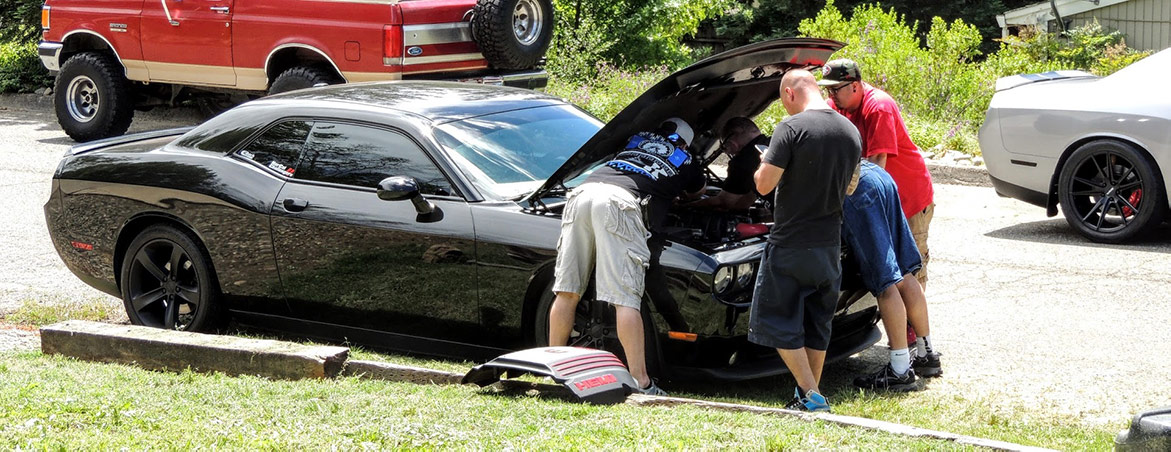 three men working on a vehicle engine