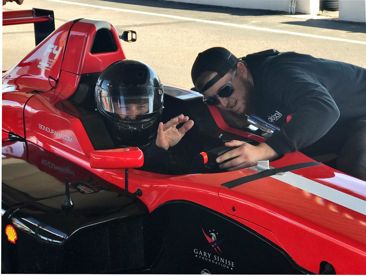 man helping another man get settled into a race vehicle