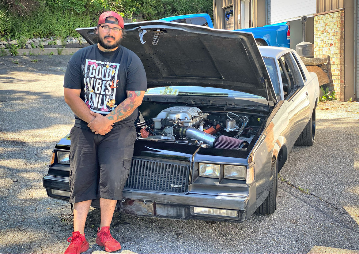 Man leaning against a vehicle with the hood open