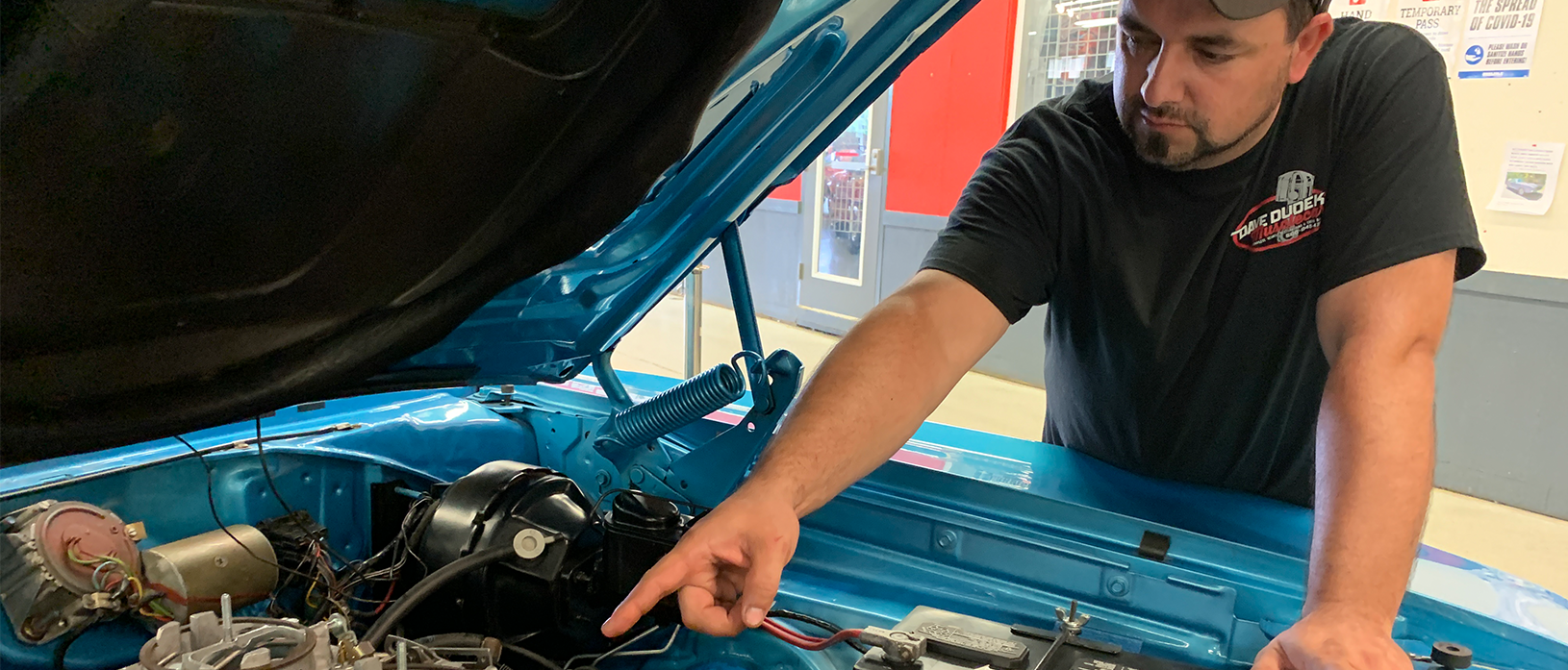 man pointing at a vehicle engine