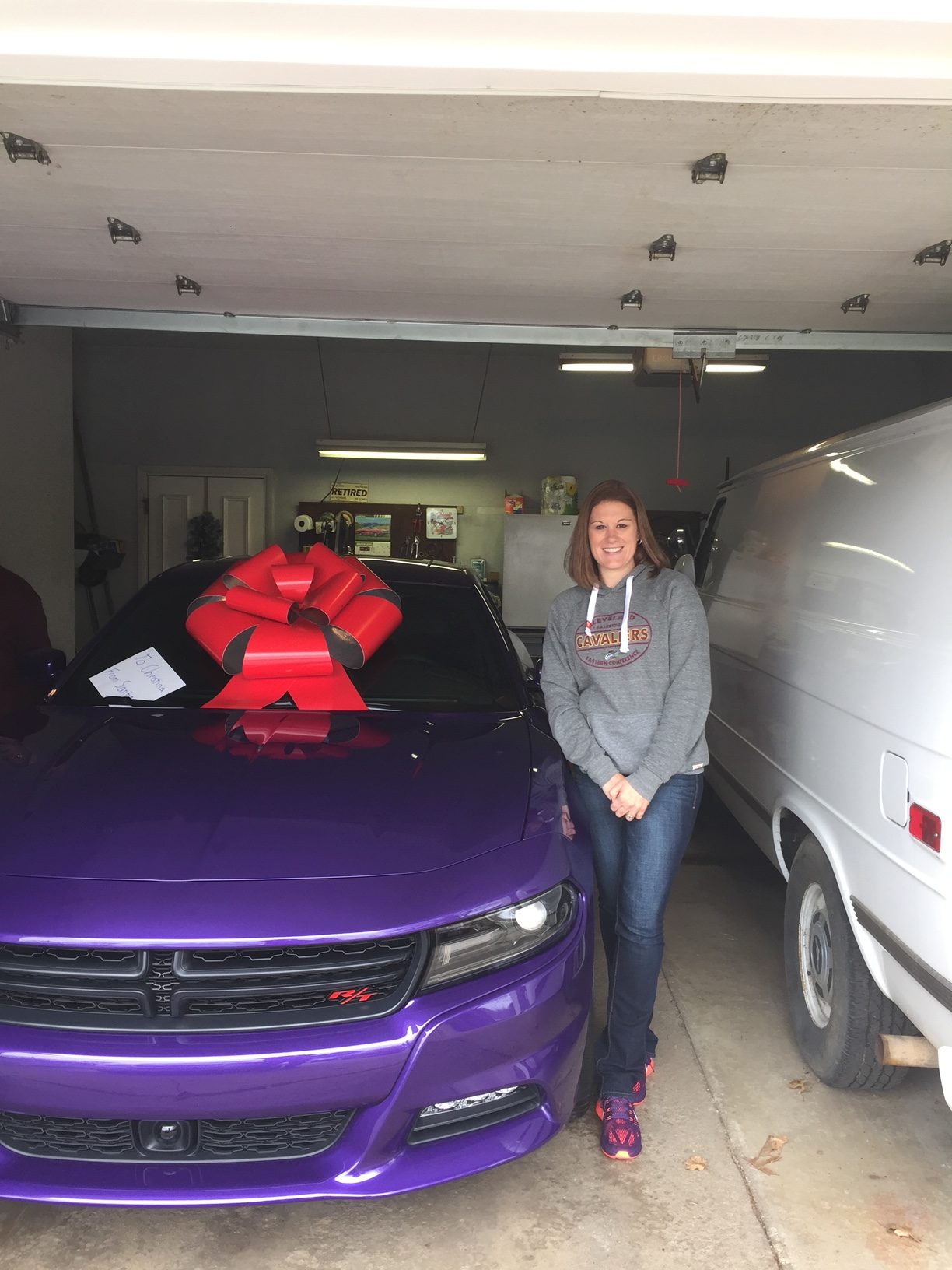Christina Nash standing by her 2016 Dodge Charger R/T with a big       red bow on top.