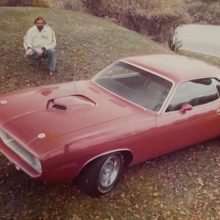 Larry Henry posing beside a classic Dodge