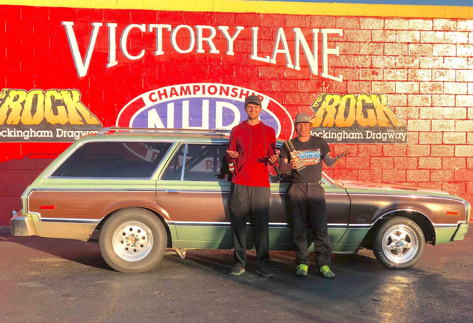 2 men standing next to a race car