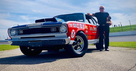 Herb McCandless standing next to his race car holding his Wally