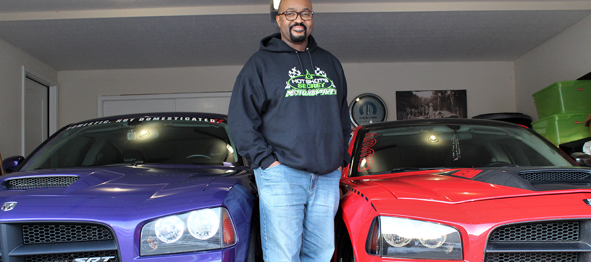 Anthony Carter standing next to his Dodge cars