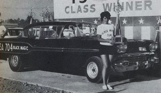 Mary Ann Foss holding a trophy while standing in front of her race car