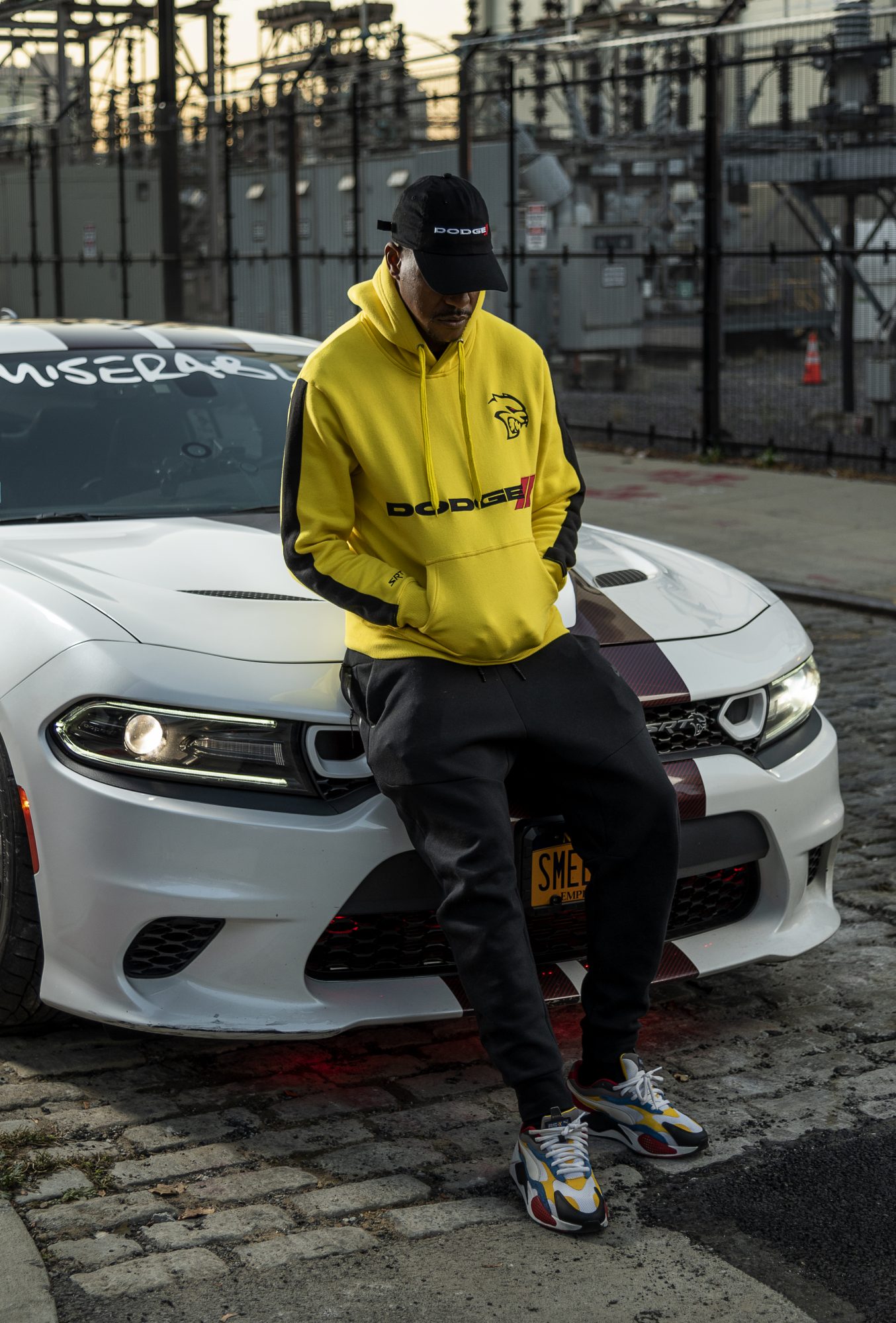 man wearing Dodge hoodie sitting on a Dodge Charger