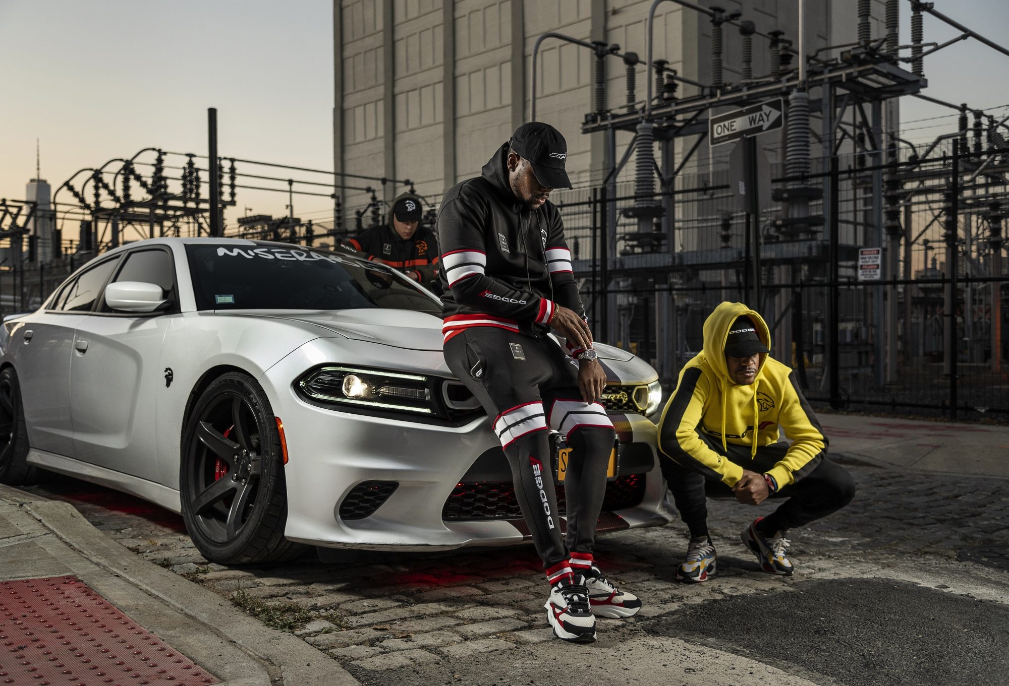 Two mend standing in front of a Dodge Charger